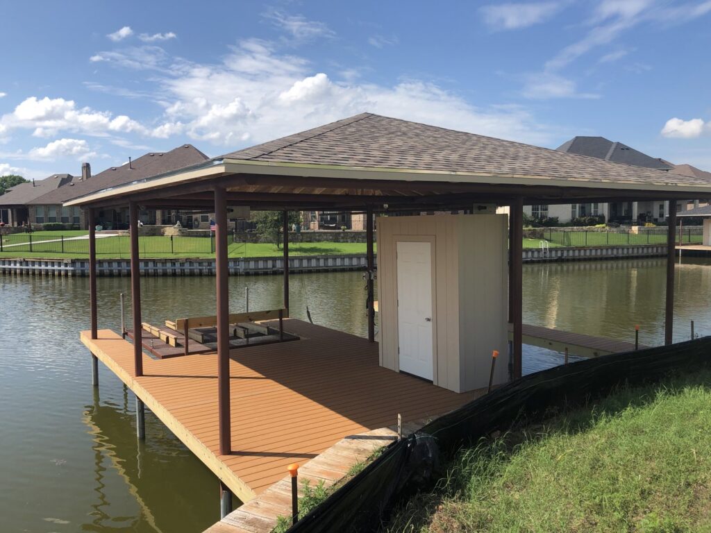 A newly constructed covered boat dock with a small storage shed over the water, built by Falls Contracting, LLC in Raleigh, NC.