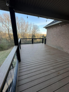 A beautifully finished covered composite deck with modern wire railings and decorative string lights, built by Matt Hingle Construction in Bowling Green, KY.