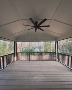 A newly built covered outdoor deck with a ceiling fan and recessed lighting by Creta Construction in Charlotte, NC.