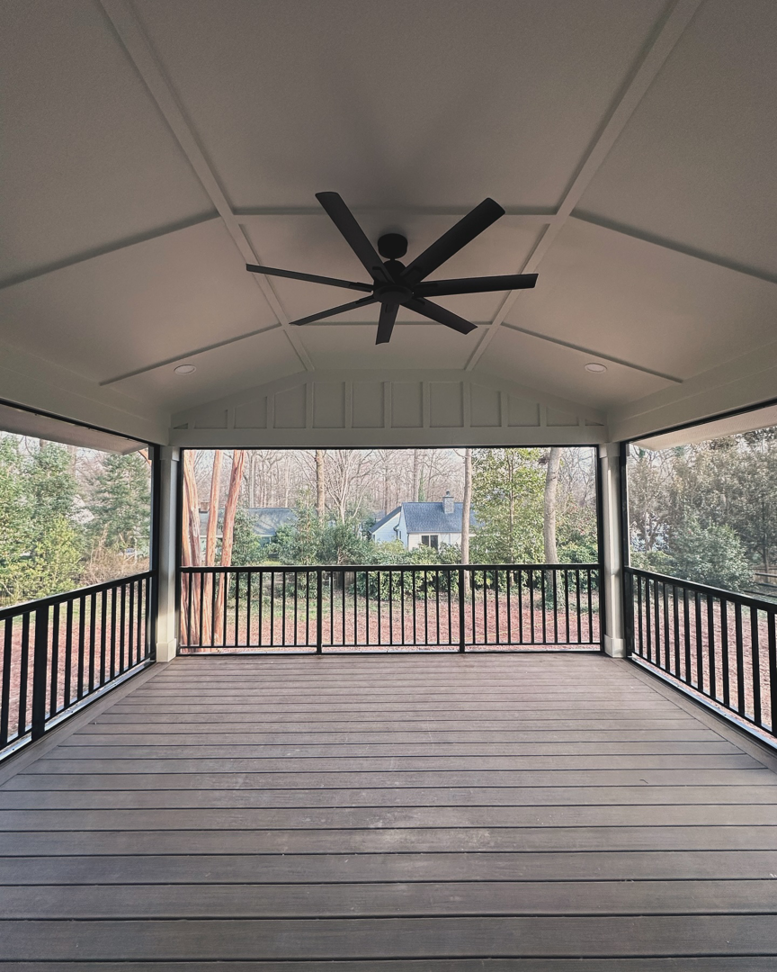 A newly built covered outdoor deck with a ceiling fan and recessed lighting by Creta Construction in Charlotte, NC.