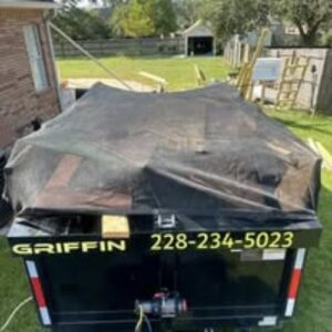 A Clutter Control Junk Removal and Demo dump trailer, covered with a tarp and full of junk, ready for transport in Biloxi, MS.