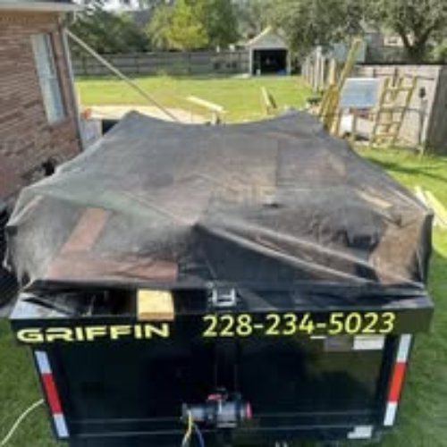 A Clutter Control Junk Removal and Demo dump trailer, covered with a tarp and full of junk, ready for transport in Biloxi, MS.