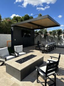 A covered outdoor living area with a TV, fire pit, and seating installed by Envy Pools in Gilbert, AZ.
