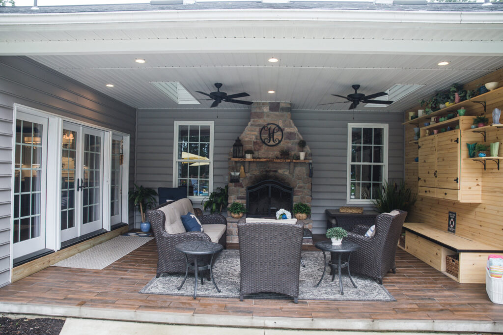 A covered outdoor patio featuring a stone fireplace and ceiling fans by Corrado Custom Homes, Inc. in Kutztown, PA