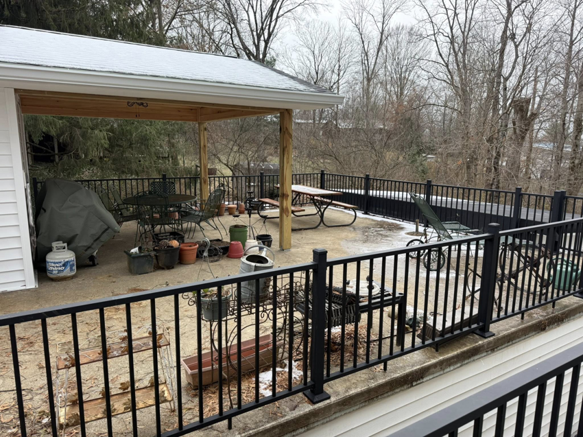A newly built covered outdoor patio with a wooden roof structure and black metal railings by Rogers Remodeling in Bloomington, IN.