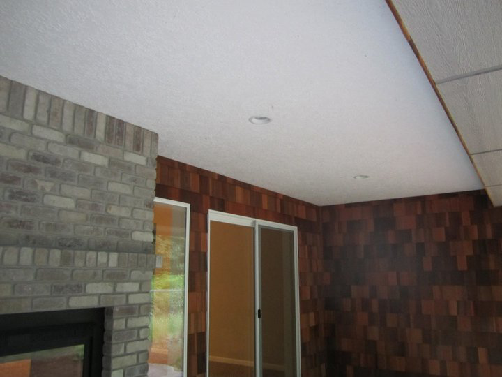 A covered patio area with a brick fireplace, cedar shake wall, sliding door, and recessed lighting by Qual-i-Tee bilt homes - Steve Johnson in Salem, OR.