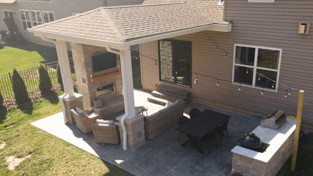 A covered patio featuring an outdoor kitchen, fireplace, and mounted TV by Rescue Landscaping and Outdoor Living in St. Louis, MO
