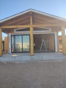 Covered patio with large sliding glass doors and wooden support beams during construction by AZ Framing and Remodeling in Peoria, AZ