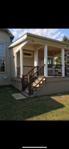 A newly constructed covered porch extension with stairs and railings on a house exterior by Nader Builders in Ann Arbor, MI.