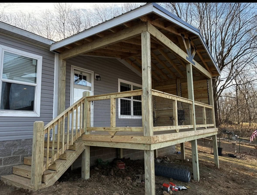 A newly constructed covered wooden porch with steps and railing by Savage Home Builders in Hodgenville, KY