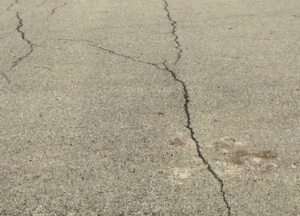 Close-up view of cracks in an asphalt surface, indicating a need for repair by Cincy SealCoating in Morrow, OH.