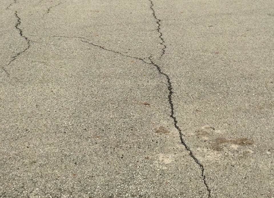 Close-up view of cracks in an asphalt surface, indicating a need for repair by Cincy SealCoating in Morrow, OH.