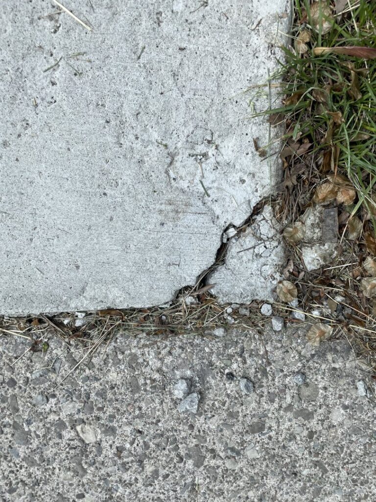 A close-up of a cracked concrete slab, indicating a need for repair services from concrete poured & installed - cp&i in Buffalo, NY.