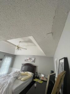 A damaged ceiling with a large crack and peeling texture before repair by Ceiling Doctor by Julian in Augusta, GA.
