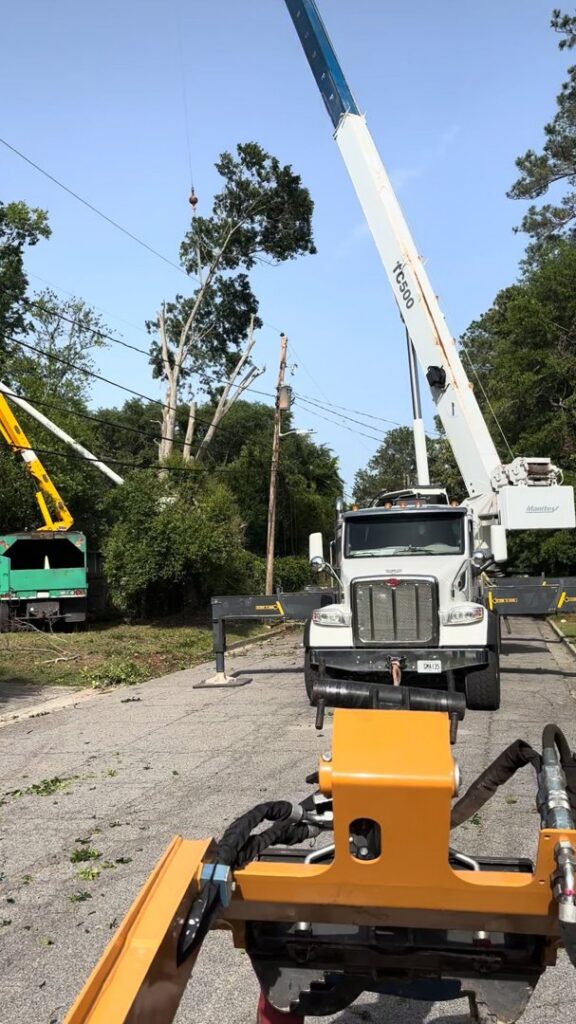 Crane and chipper trucks on a street performing tree removal and chipping services for 706 Tree and Stump in Augusta, GA.
