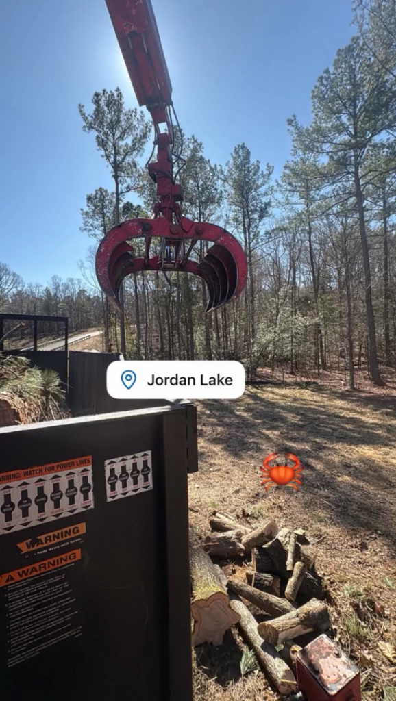A large crane grapple moving cut logs during a tree removal job by MacNeela's Tree Service in Durham, NC