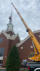 A large crane lifting a structure onto a church steeple for restoration by Azure Construction in Clarksville, TN