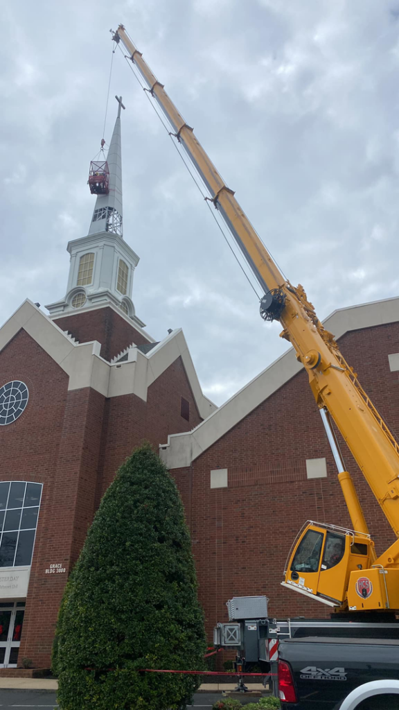 A large crane lifting a structure onto a church steeple for restoration by Azure Construction in Clarksville, TN