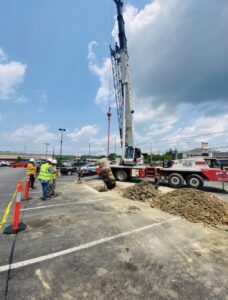 A crane lifting a heavy object from a construction site in a parking lot by Specialty Service Group in Knoxville, TN.