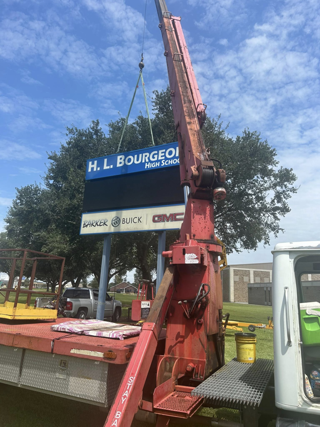 A crane lifting a component of the H. L. Bourgeois High School sign during installation by B & H Metal Buildings Inc. in Kenner, LA.