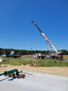 A large crane from Tidewater Crane & Contracting lifting industrial equipment at a job site in Virginia Beach, VA