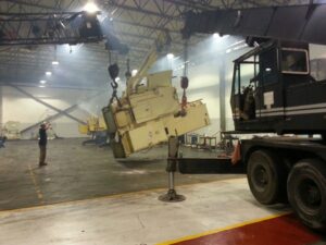 A crane from Tidewater Crane & Contracting lifting industrial machinery inside a factory in Virginia Beach, VA