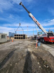 A crane from Tidewater Crane & Contracting lifting a large rectangular structure outdoors in Virginia Beach, VA