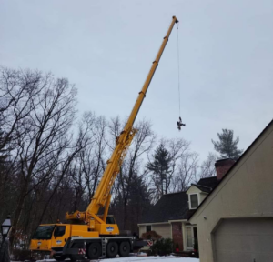 A large crane lifting a worker or equipment for safe tree removal by Out On A Limb Tree Service in Lowell, MA.