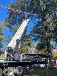 A large crane removing a tree near power lines for Tates Tree Service in Shalimar, FL.