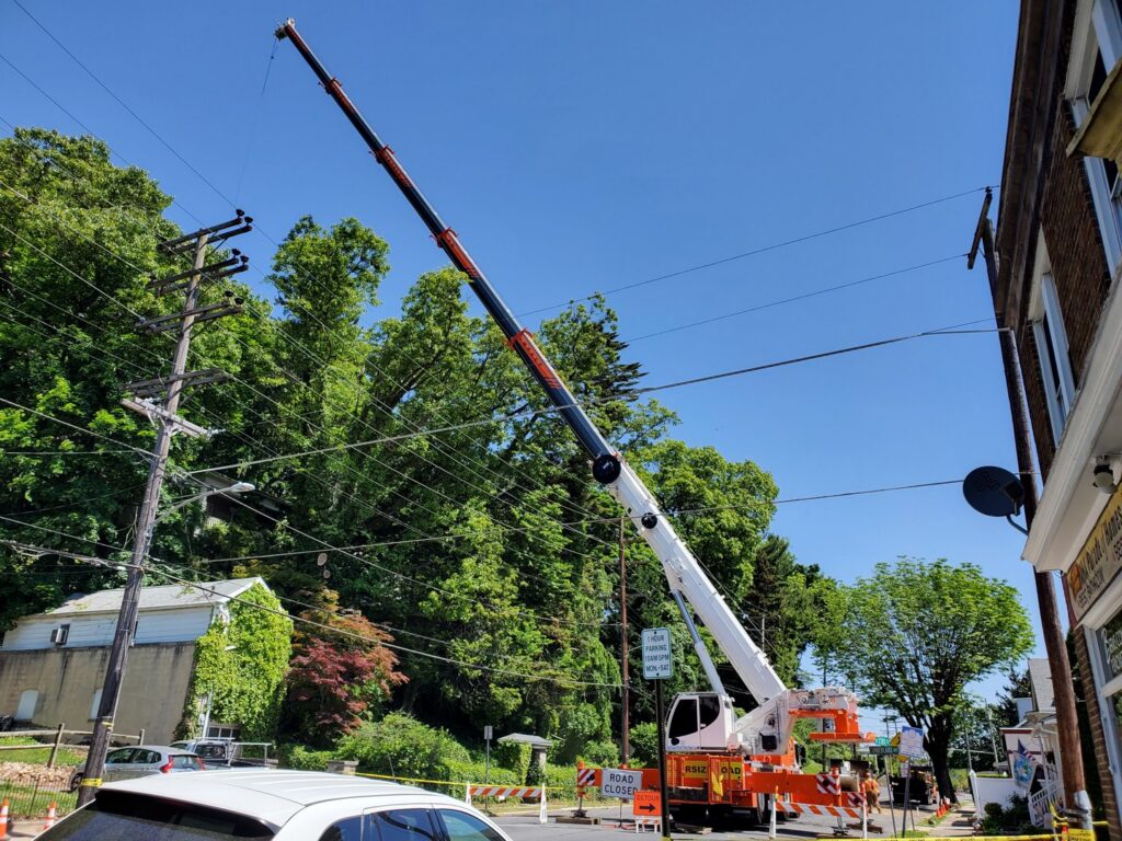 A large crane assisting with complex tree removal near power lines by Morgan Brothers Tree Care Solutions in Birdsboro, PA