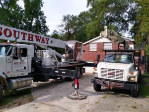 A crane truck and another service vehicle parked in a driveway for tree removal by Arbor Elite SC in Columbia, SC.