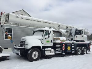 A large crane truck with the Scott Lanes Tree Service logo, parked and covered in snow in Chesapeake, VA.