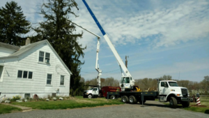 A crane truck and bucket lift equipment set up for tree removal by Baltimore Tree Experts in Baltimore, MD.