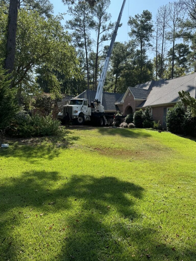 A large crane truck set up for tree removal or trimming services in front of a residential house by Tri-County Tree And Restoration in Jackson, MS.