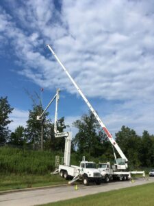 Two large crane trucks working together to remove a tree section, performed by Jon's Tree Service in Pelham, AL.