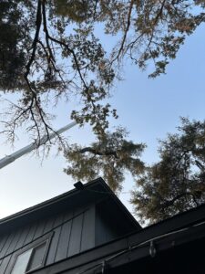 A crane from Eagerton Tree Service, LLC working on a tree extending over a residential house in Ponte Vedra Beach, FL.