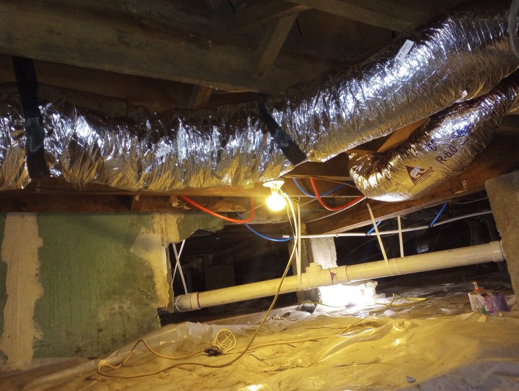 Crawl space showing ductwork, plumbing pipes, and wiring during an inspection or service by Pollock HVAC & Electrical in Albany, GA
