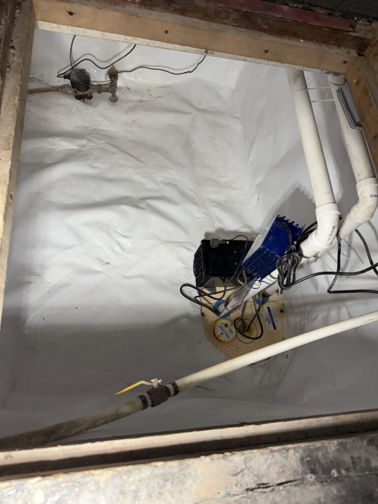 A crawl space encapsulated with a white vapor barrier and sump pump system by Woodford Bros., Inc. in Apulia Station, NY