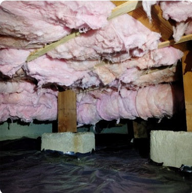 Detailed view of a crawl space showing pink insulation, concrete support piers, and a black vapor barrier installed by Northwest Crawl Space Services in Kent, WA.