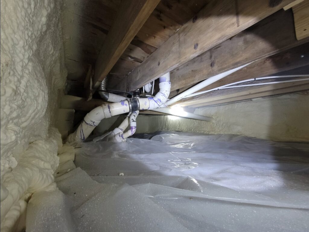Crawl space with spray foam insulation on the walls and plastic vapor barrier, completed by Spray Foam Solutions Of Erie in Erie, PA.