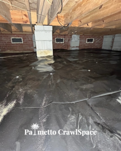 A crawlspace showing a newly installed black vapor barrier by Palmetto Crawlspace, providing moisture control in Mount Pleasant, SC.