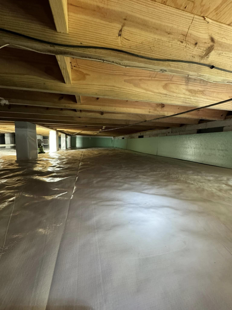 A crawlspace with a white vapor barrier and green insulation boards installed by Humidi-Seal Crawlspace Solutions in Charleston, SC.
