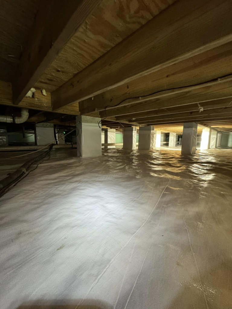 A crawlspace with a white vapor barrier and a large pipe, completed by Humidi-Seal Crawlspace Solutions in Charleston, SC.