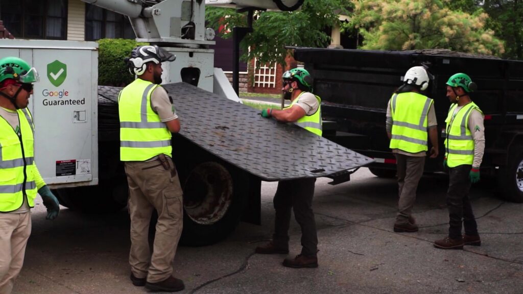 Longtree Tree Service crew carrying ground protection mats during a job in Southfield, MI.