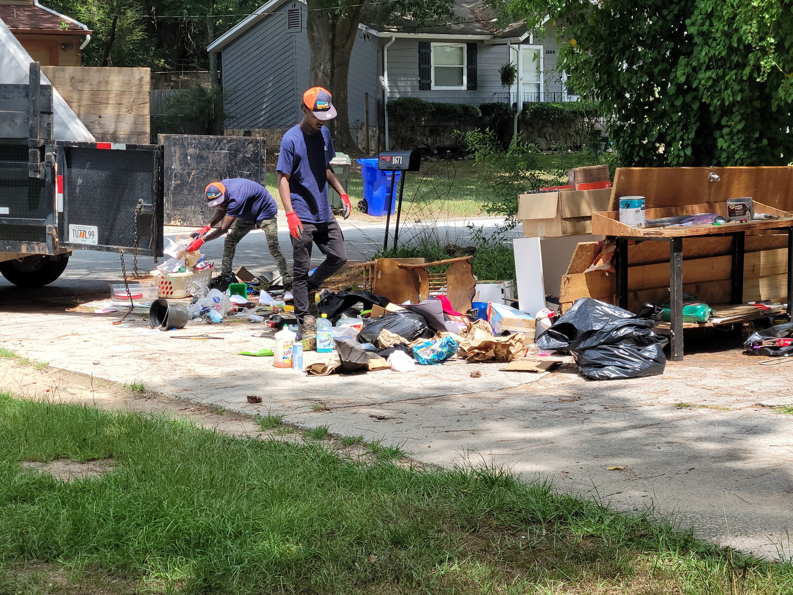 GoGo Junk Removal crew cleaning up a pile of trash and debris from a driveway in Atlanta, GA.