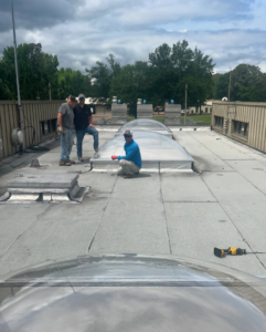 A crew inspecting a commercial flat roof with multiple skylights for Elite Roofing Solutions in Bartlett, TN.