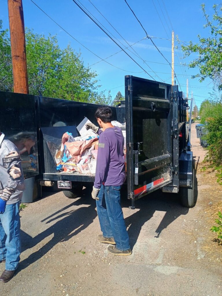 A crew loading various items into a dump trailer during a junk removal job by T-Rex Service LLC in Cheyenne, WY.