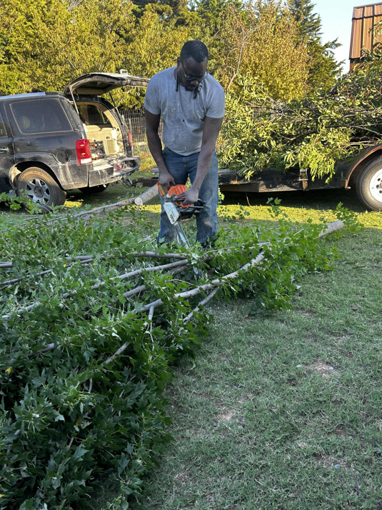 A crew member from Zulu's Lawn & Tree service cutting fallen branches with a chainsaw in Lawton, OK.