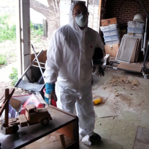 A crew member in a hazmat suit and mask performing a junk removal cleanup job for El Paso Junk Removal and Hauling in El Paso, TX.