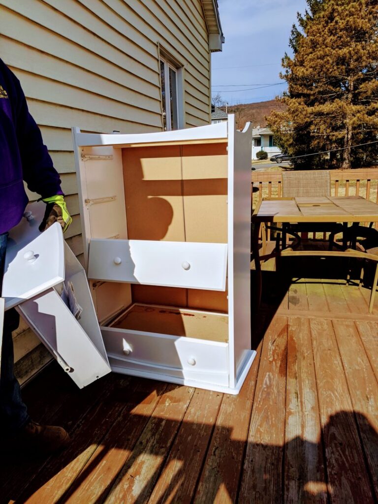 A crew member from Junken Monkeys Hauling Company removing a white dresser from a wooden deck during a junk removal job in Scranton, PA.